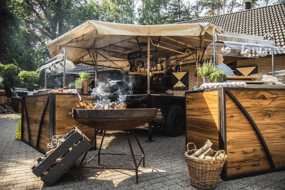 Veldkeuken foodtruck met live BBQ en ambachtelijke bereiding op buitenevent