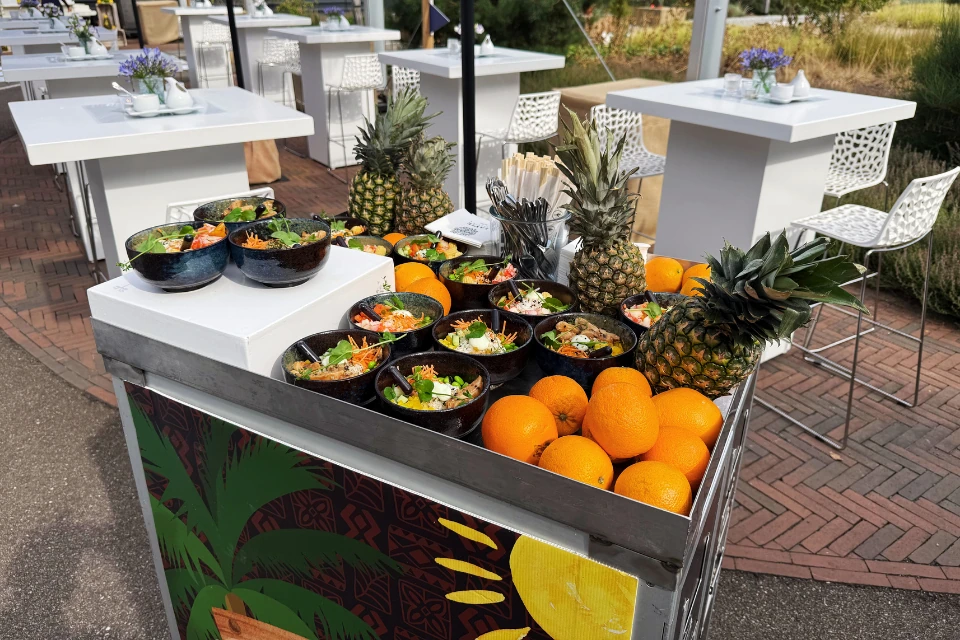 Vliegtuigtrolley met verse poké bowls en gepersonaliseerde logoplaten tijdens zakelijk event